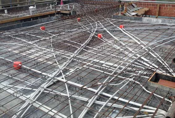 Conduit bends and junction boxes laid across steel mesh on a slab.